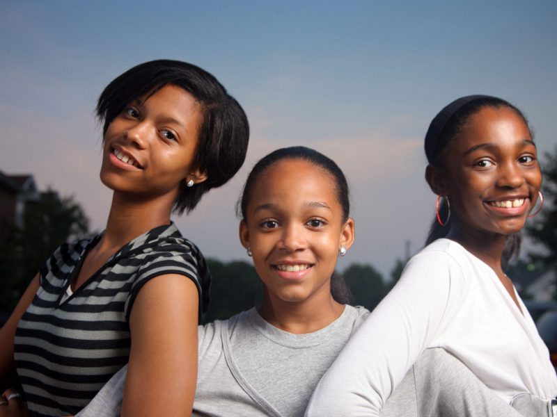 Three beautiful smiling teenage African American girls outdoors