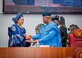 Elegant Nigerian woman in traditional blue attire shaking hands with official in blue traditional robe during formal event at the senate chamber.
