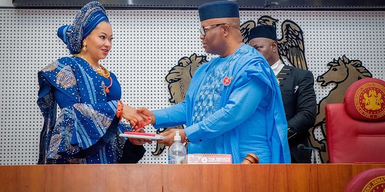 Elegant Nigerian woman in traditional blue attire shaking hands with official in blue traditional robe during formal event at the senate chamber.