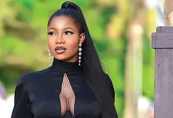 Stunning woman in black outfit with long hair and elegant earrings outdoors, showcasing fashion and style for lifestyle and beauty-related content.