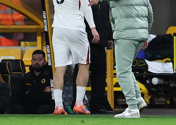 A football player with jersey number 9, Delap, receiving medical attention from a staff member on the sidelines during a match. Other staff and a security personnel are visible in the background.