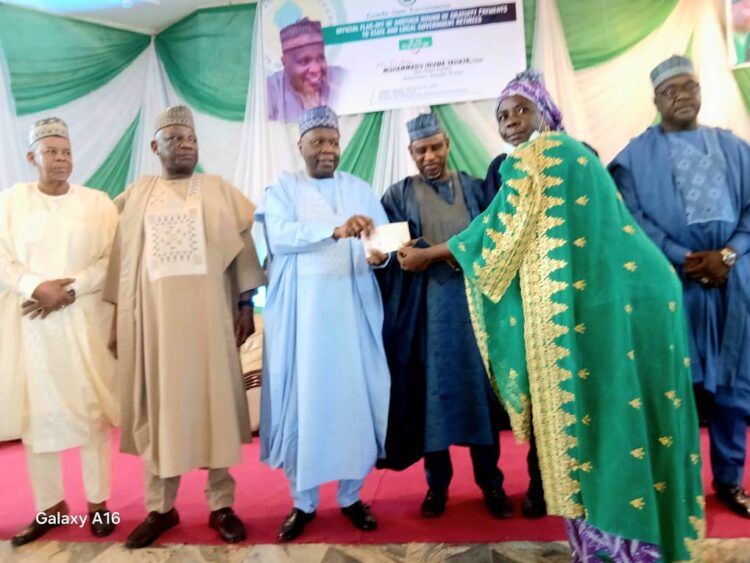 Award ceremony in Nigeria, with traditional attire and Nigerian flag in background, celebrating achievements with dignitaries and community leaders.