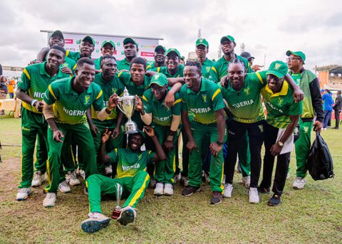 Nigerian cricket team celebrating victory with trophy, wearing green kits, on the field after a match; team spirit, national pride, and sporting success highlighted.
