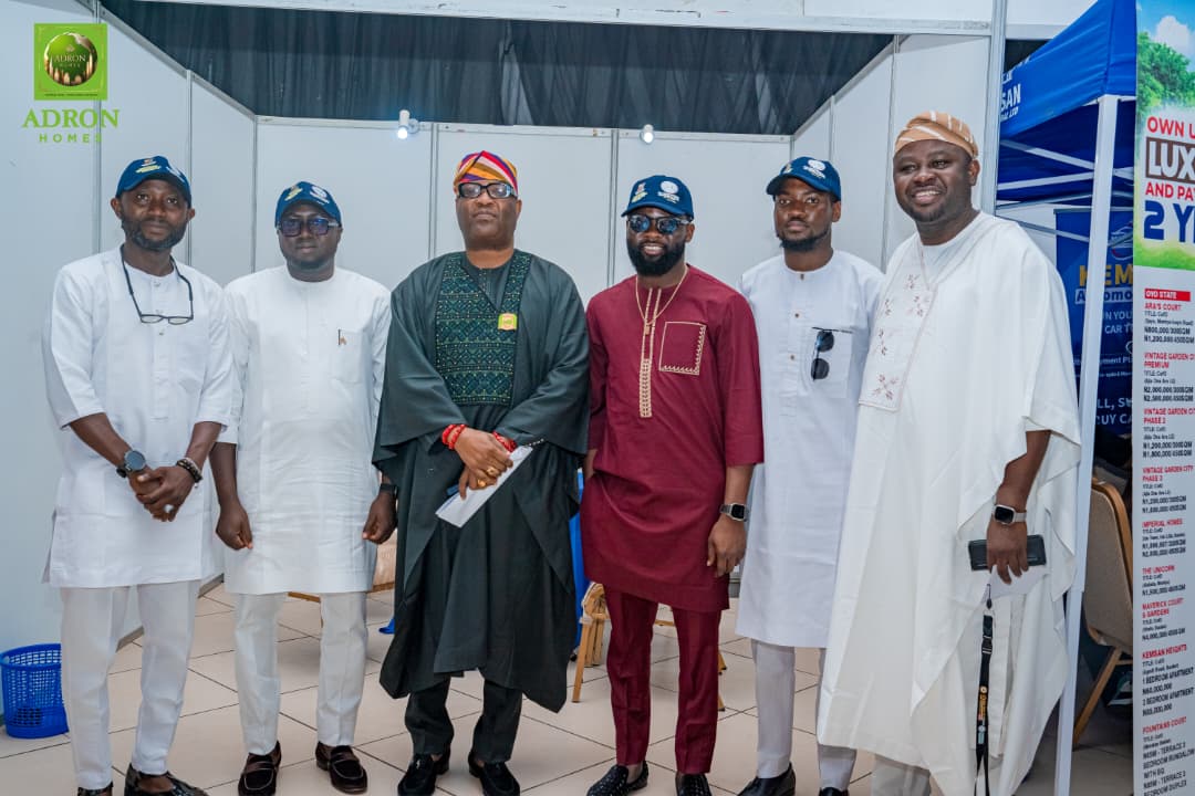 African men at a professional event wearing traditional and modern attire, standing in front of an exhibition booth, promoting business, networking, and diversity in the workplace for Freelanews.