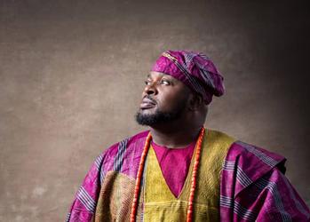 Elegant African man in traditional colourful attire, looking thoughtfully into the distance, symbolising cultural pride and heritage, suitable for articles on cultural fashion and identity.