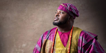 Elegant African man in traditional colourful attire, looking thoughtfully into the distance, symbolising cultural pride and heritage, suitable for articles on cultural fashion and identity.