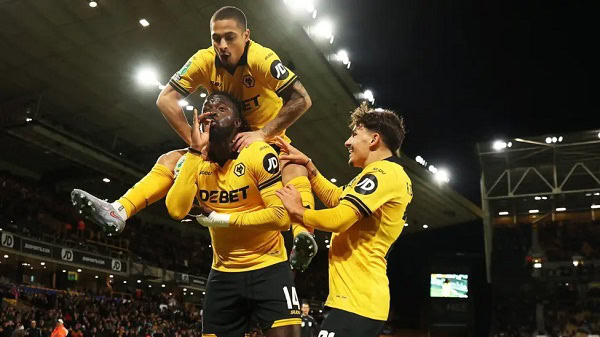 Vibrant football players wearing yellow kit celebrating a goal during a match at a packed stadium, showcasing their teamwork and excitement.