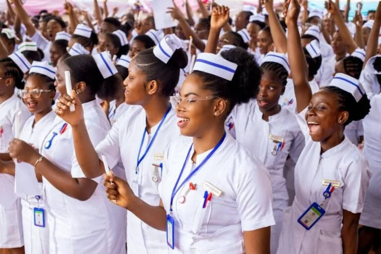 Bright African nurses in white uniforms celebrate and cheer at a healthcare event, embodying healthcare workers' dedication, unity, and community engagement.
