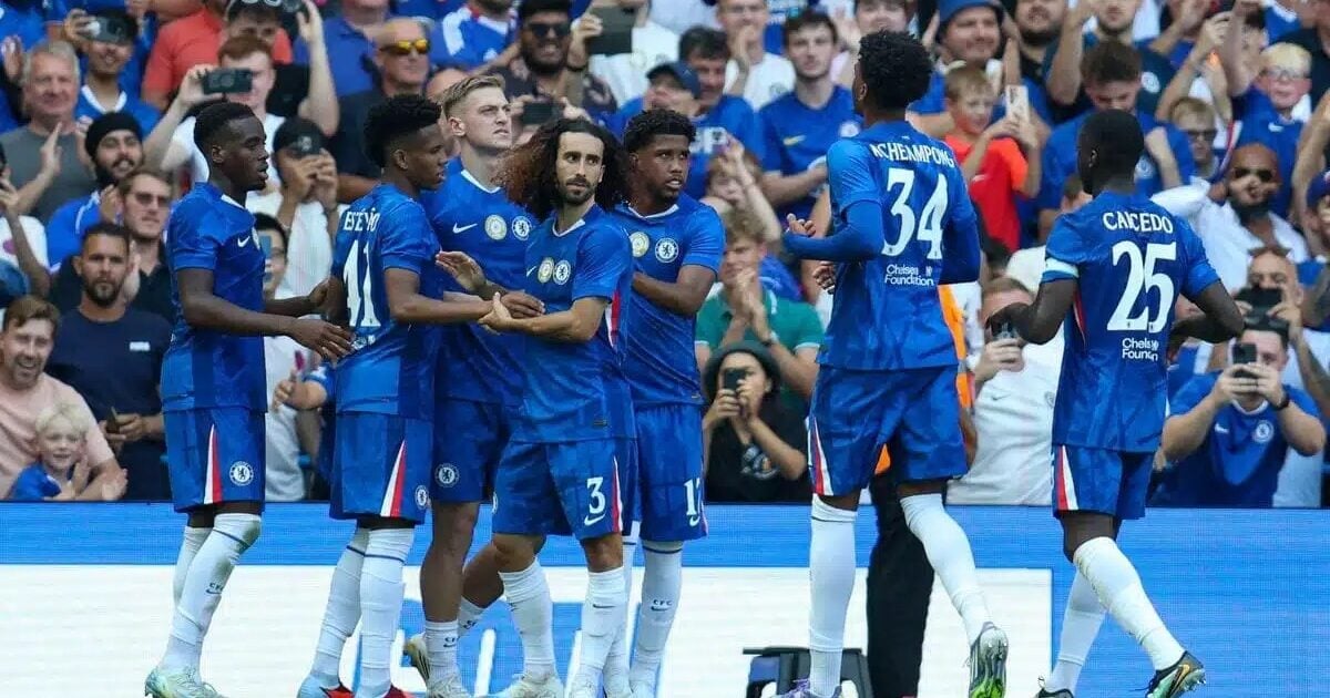 Chelsea football team celebrating on the pitch with fans in the background, showcasing teamwork and sportsmanship during a match.