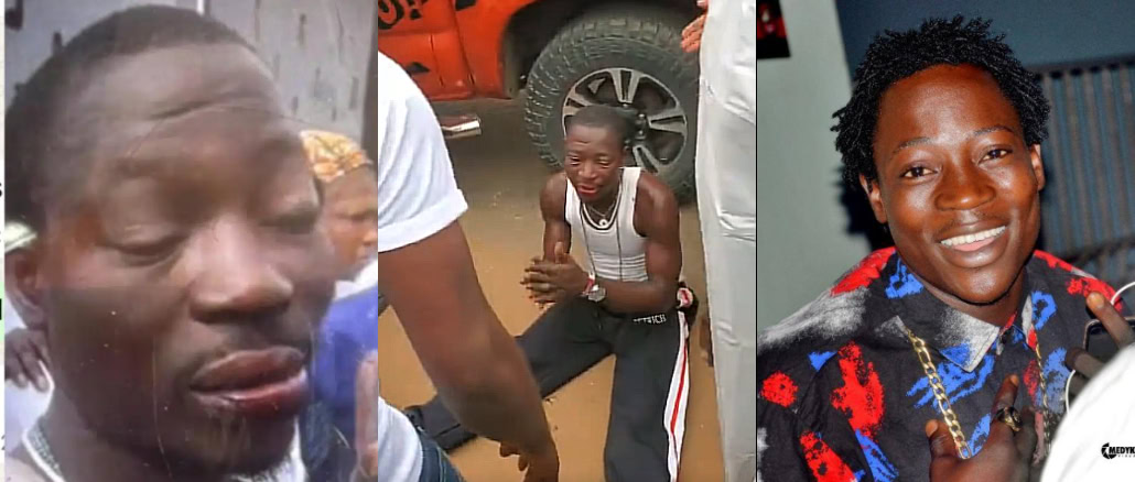 Sad young man crying in distress in a crowded outdoor setting.