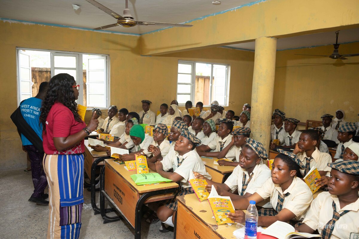 Students in classroom attending an educational workshop in Africa with teacher instructing, books and notebooks on desks, learning environment, school supplies, classroom activity, African education setting, student engagement.