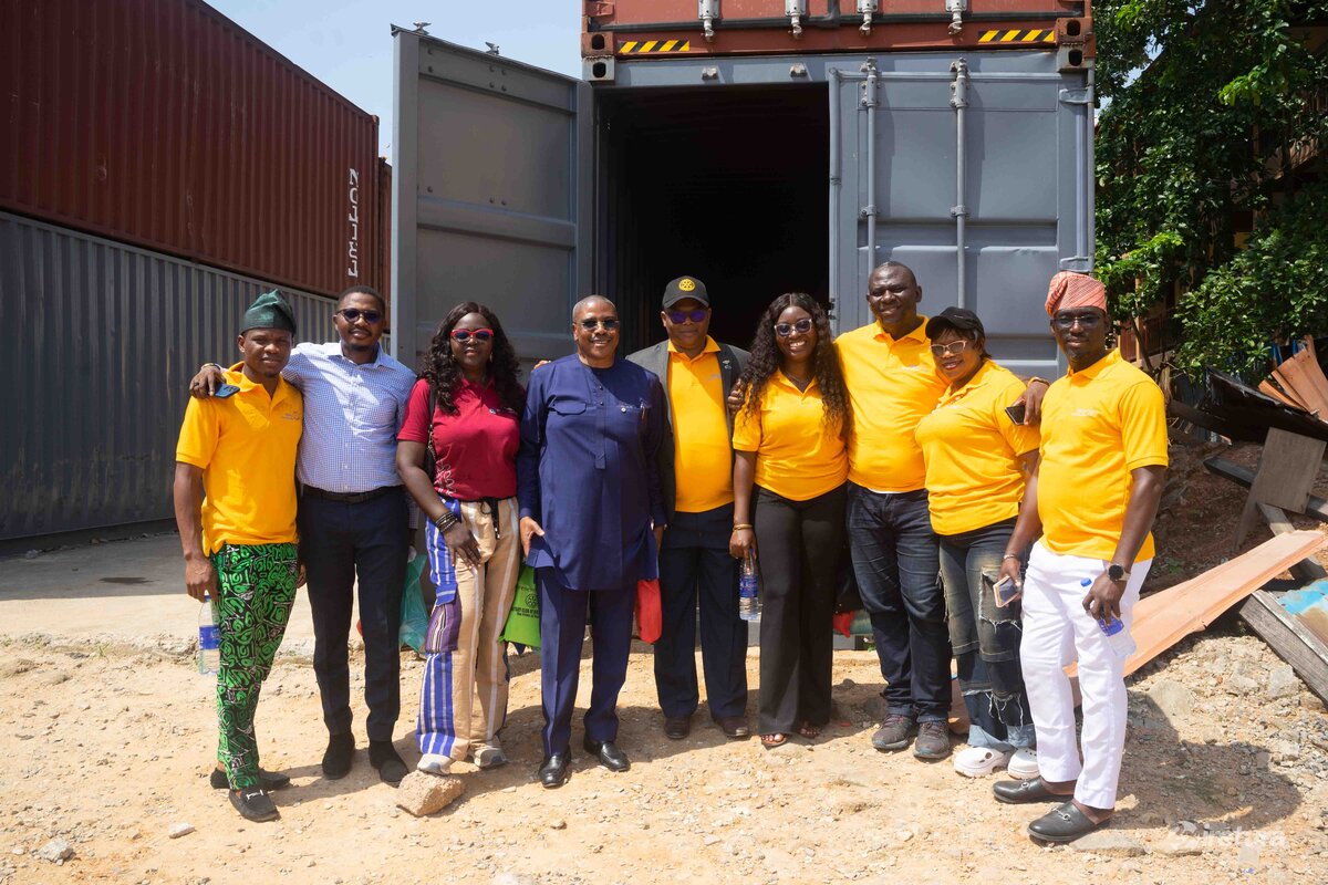 Container donation event in an outdoor setting with a diverse group of people in vibrant clothing, symbolising community support and teamwork for a charitable cause.