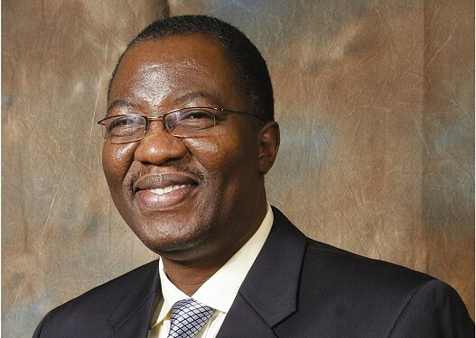 Successful professional African man in a business suit with glasses, smiling confidently at the camera.