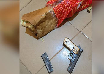 Unsecured firearm and ammunition on tiled floor alongside a torn bread bag, highlighting safety hazards and the importance of gun security in homes.