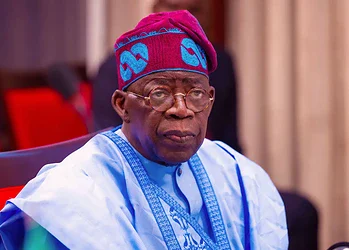 Elderly man wearing traditional Yoruba attire and red and blue cap, sitting in a formal setting, reflecting Nigerian cultural heritage and leadership.