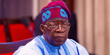 Elderly man wearing traditional Yoruba attire and red and blue cap, sitting in a formal setting, reflecting Nigerian cultural heritage and leadership.
