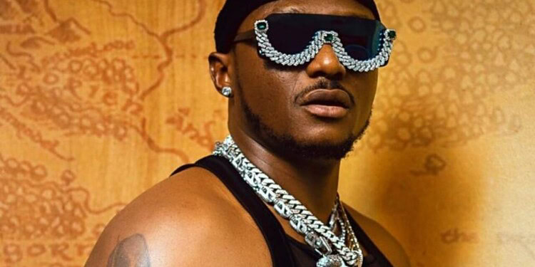 Vibrant portrait of a man wearing oversized sunglasses with jewel embellishments, layered chains, and stylish accessories, highlighting modern fashion and bold personal style.