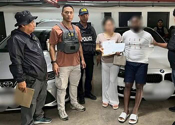 Suspected individuals detained by police officers in an underground parking garage in Thailand, with a luxury BMW car in the background, as part of a crime investigation.