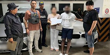Suspected individuals detained by police officers in an underground parking garage in Thailand, with a luxury BMW car in the background, as part of a crime investigation.