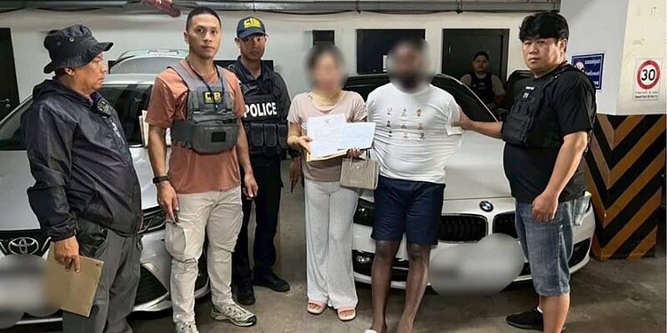 Suspected individuals detained by police officers in an underground parking garage in Thailand, with a luxury BMW car in the background, as part of a crime investigation.