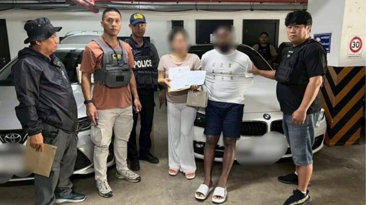 Suspected individuals detained by police officers in an underground parking garage in Thailand, with a luxury BMW car in the background, as part of a crime investigation.