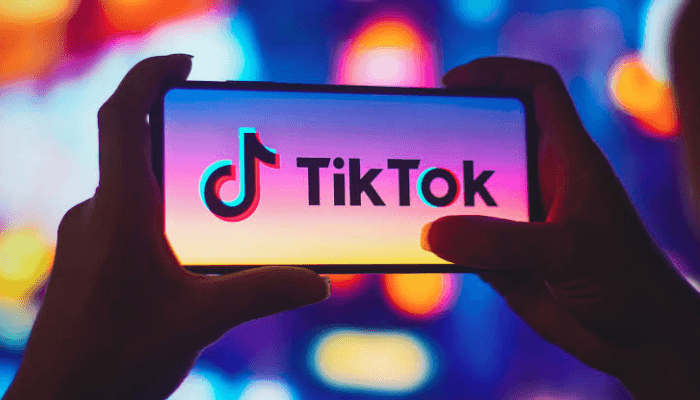 TikTok logo displayed on a smartphone screen, with colourful blurred background, representing popular social media platform for short videos and digital content creation.