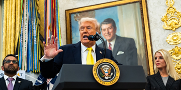 Donald Trump speaking at a podium with the presidential seal, flanked by his advisors, in a room decorated with gold accents and large portraits.
