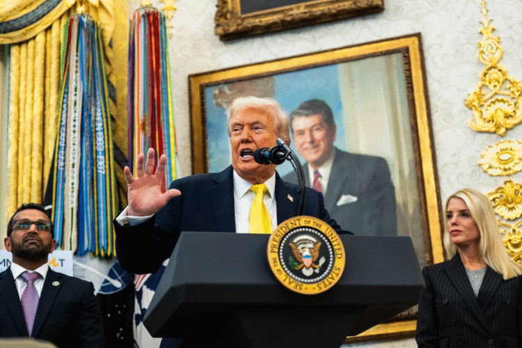 Donald Trump speaking at a podium with the presidential seal, flanked by his advisors, in a room decorated with gold accents and large portraits.