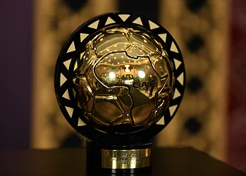 Shiny golden football trophy with black triangular accents, displayed on a stand, symbolising excellence in football awards.