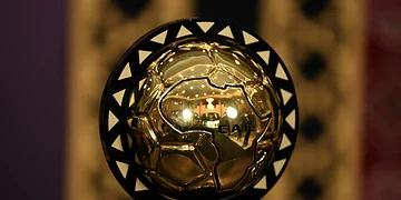 Shiny golden football trophy with black triangular accents, displayed on a stand, symbolising excellence in football awards.