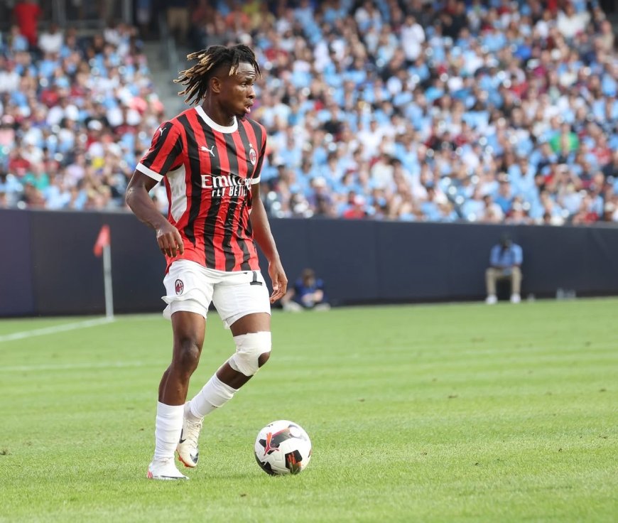 1. African football player in AC Milan jersey dribbling soccer ball on pitch during match with crowd in stadium.