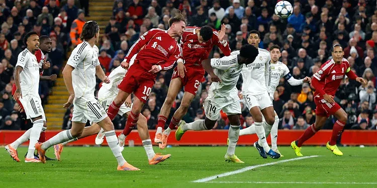 Vibrant soccer match between Real Madrid and Bayern Munich with players jumping to head the ball during a high-stakes Champions League game. Fans cheer in a packed stadium.