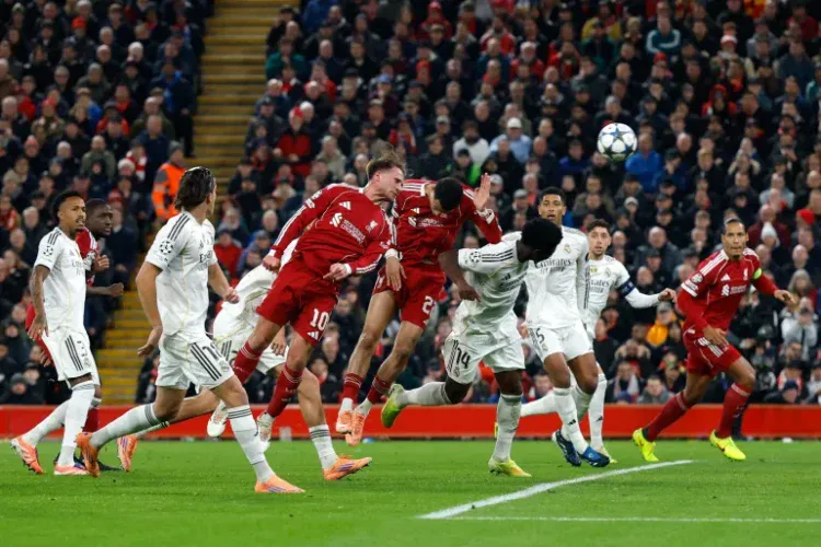 Vibrant soccer match between Real Madrid and Bayern Munich with players jumping to head the ball during a high-stakes Champions League game. Fans cheer in a packed stadium.