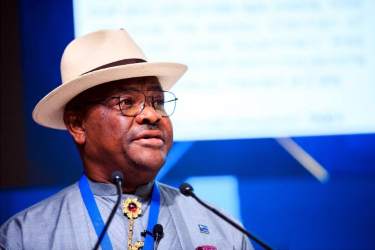 Inspirational African leader in traditional clothing and hat speaking at international event, inspiring audiences with leadership insights.